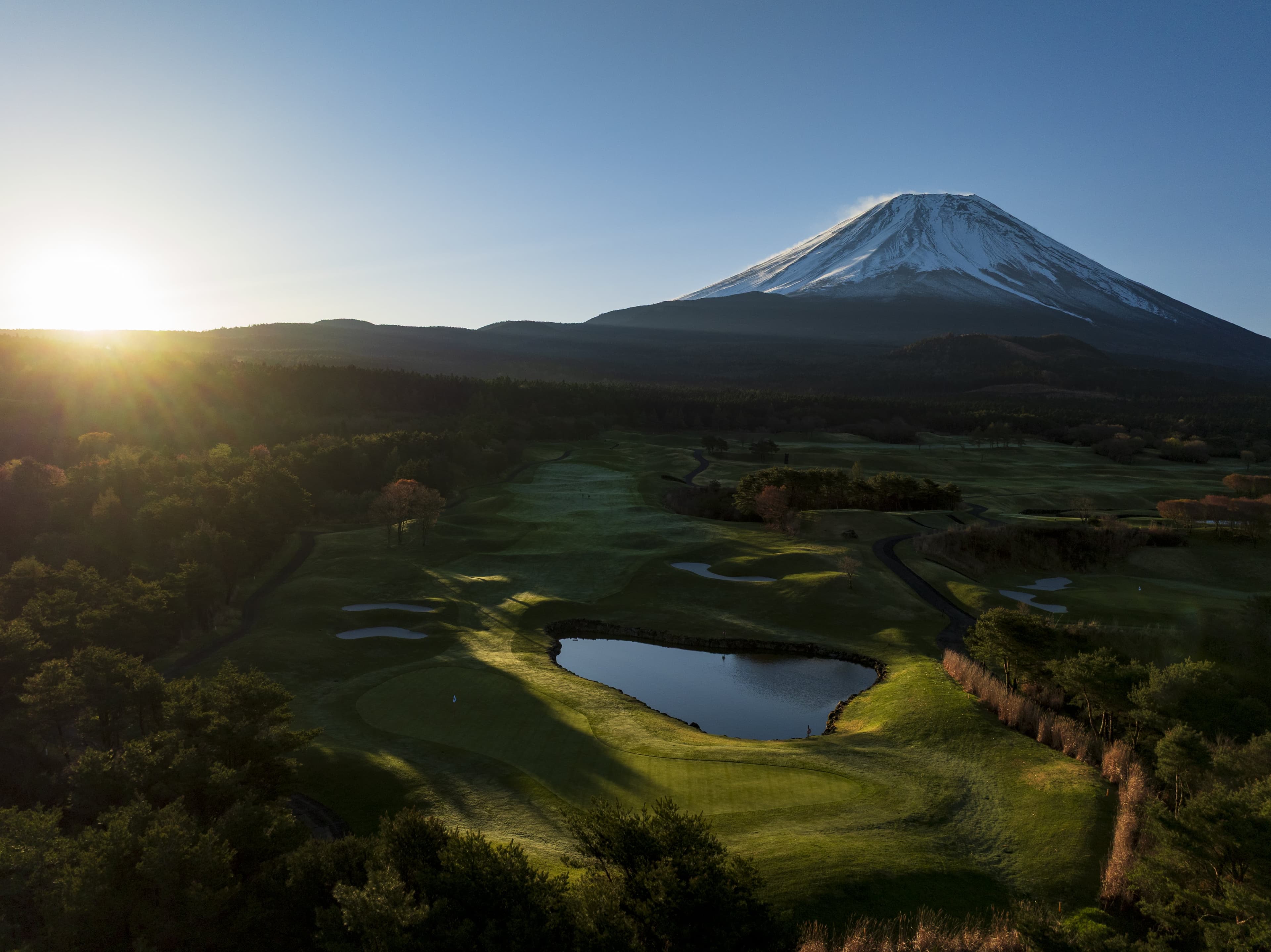 Hole 7 at Fuji Classic — sunrise over the pond-guarded fairway with Mt. Fuji beyond