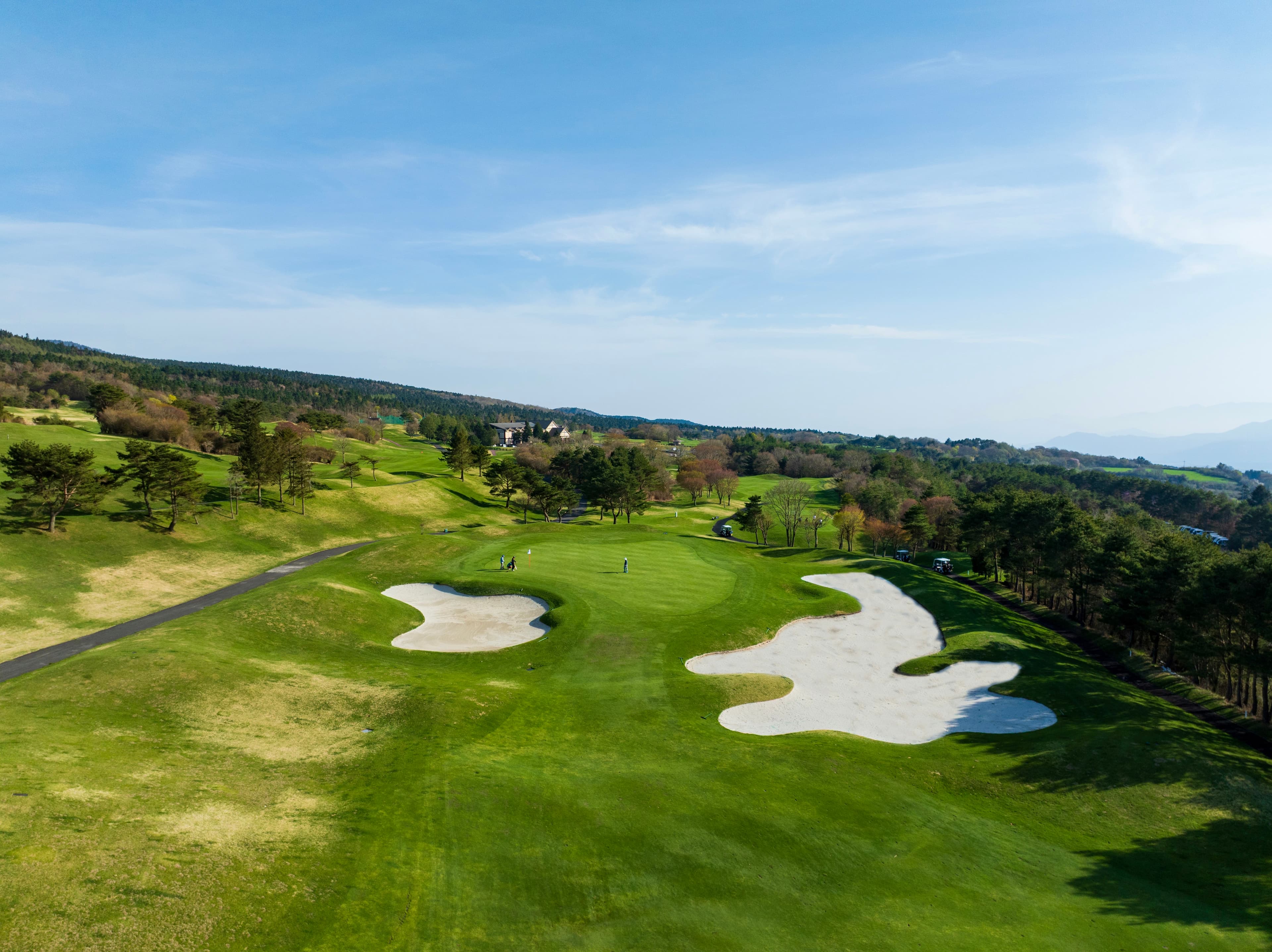 Hole 8 at Fuji Classic — white sand bunkers framing the green in a wooded valley