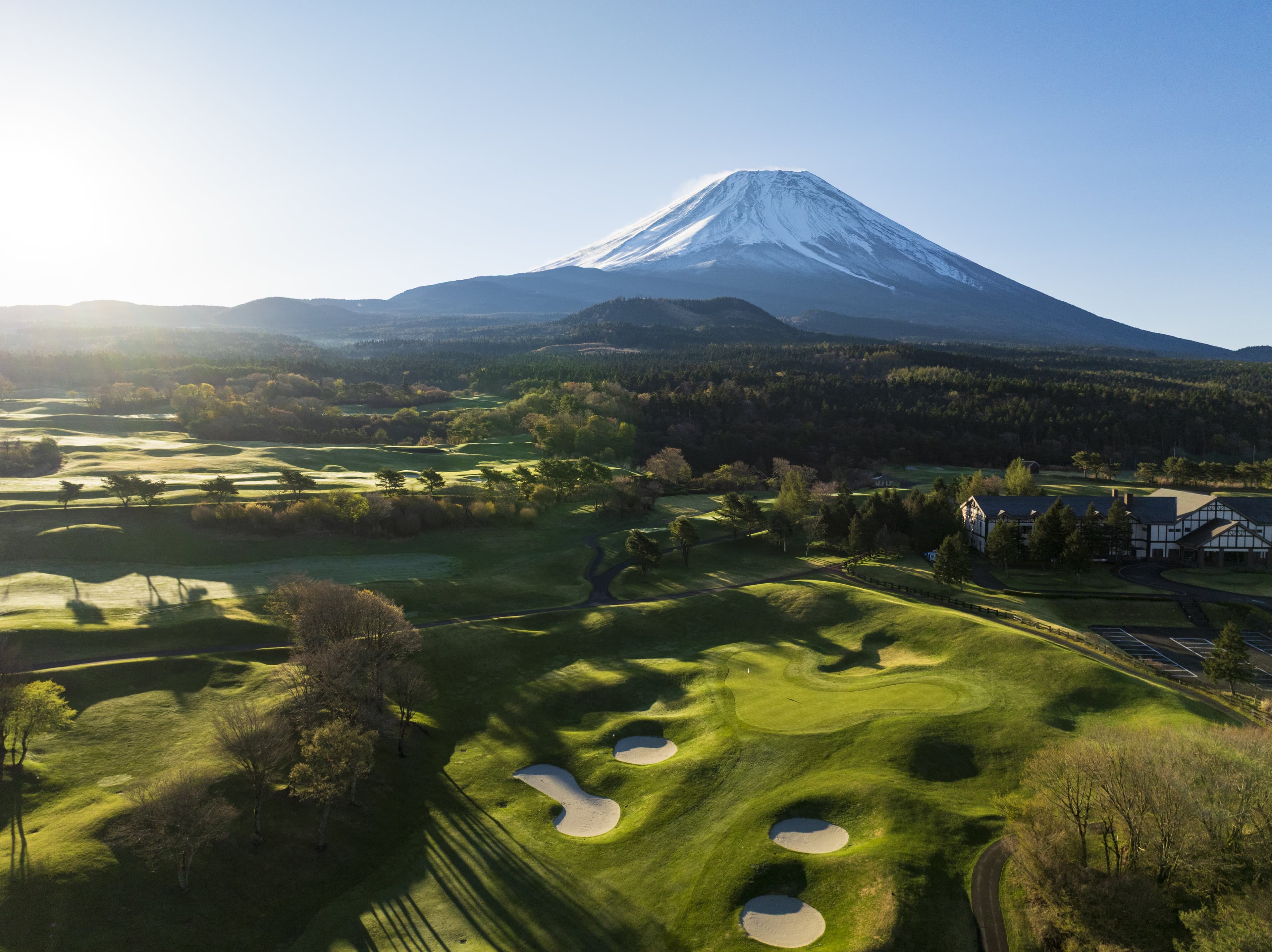 Aerial of the clubhouse and bunkered fairways beneath Mount Fuji