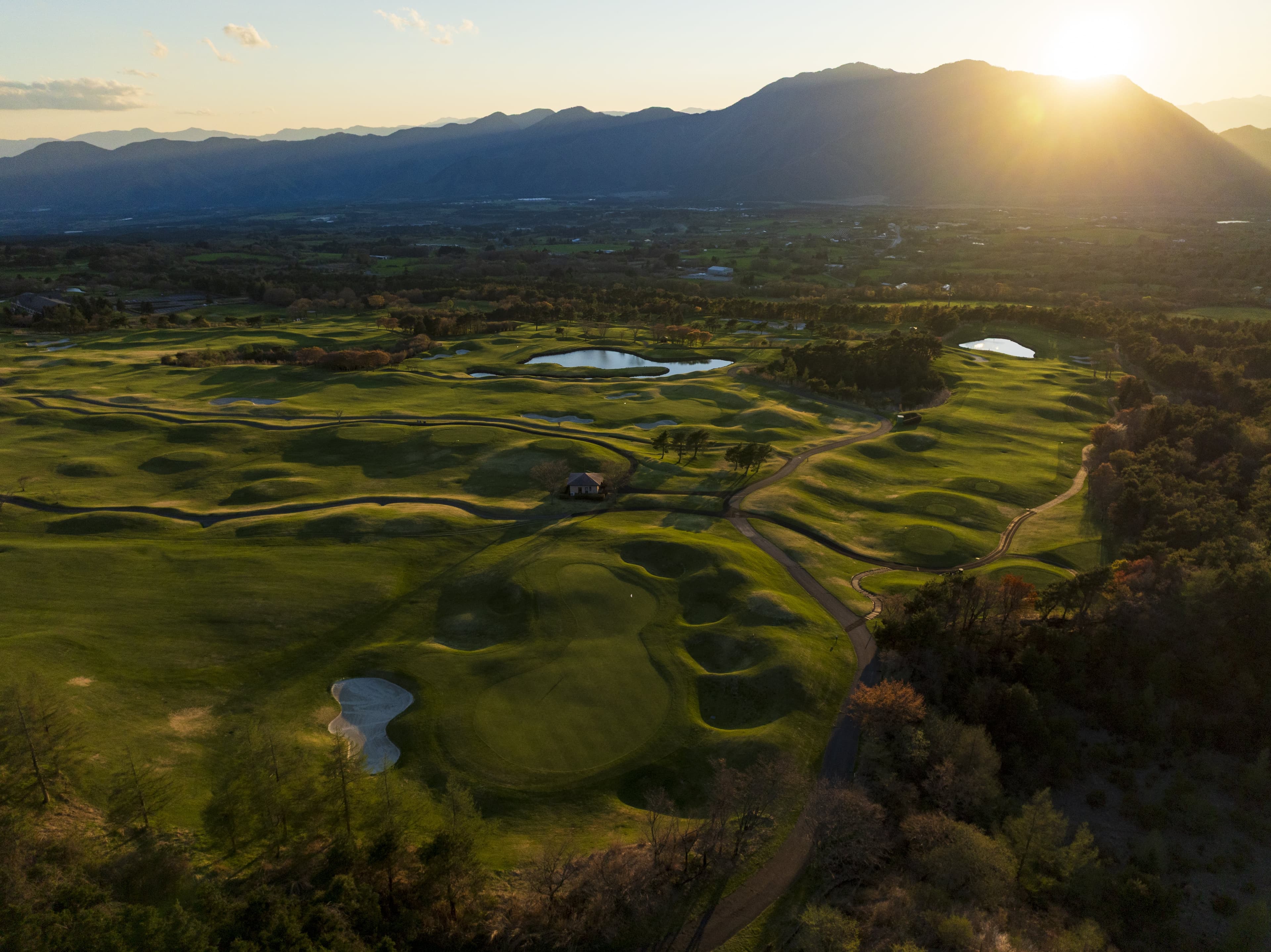 Sunset sinking behind the mountain ridge over contoured fairways