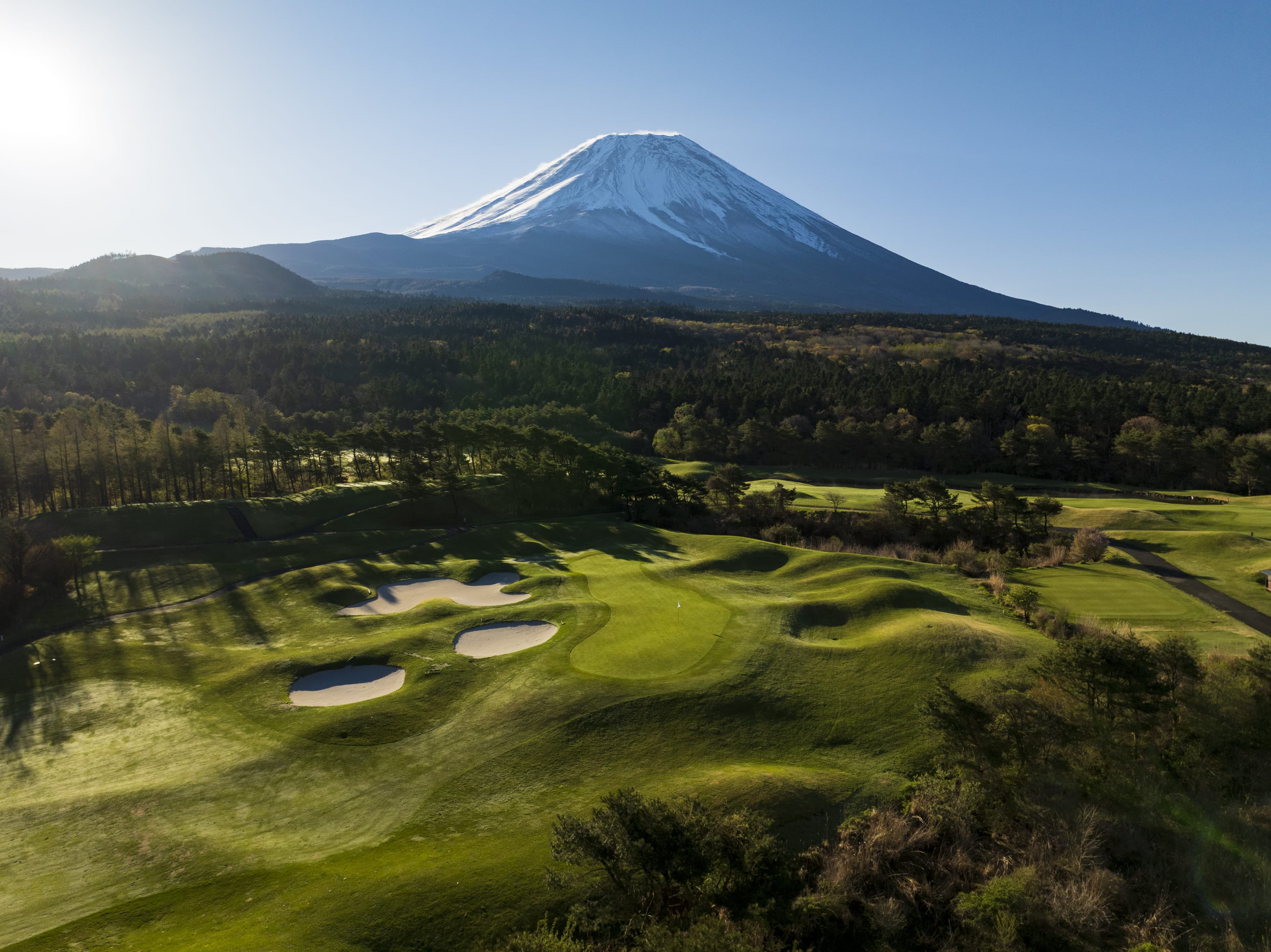 Hole 14 at Fuji Classic — shadowed bunkers and green with Mt. Fuji rising behind